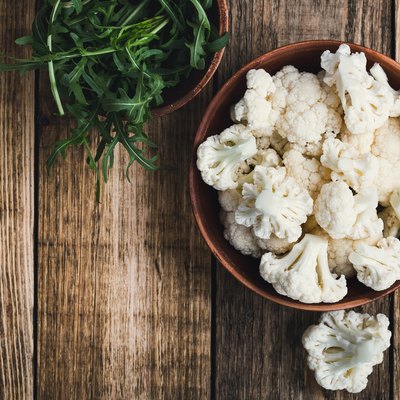 Fresh organic cauliflower cut into small pieces in a bowl. Vegetarian recipe or menu background with copy space