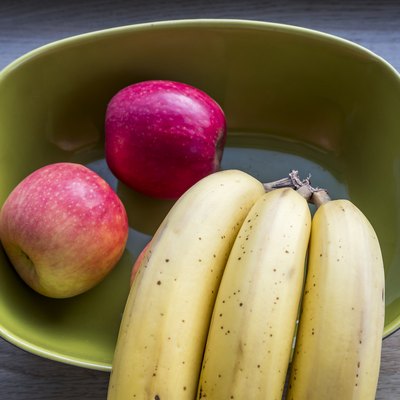 Fresh apples and bananas on green bowl
