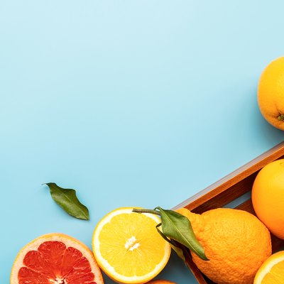 Various citrus fruit on blue background top view with copy space