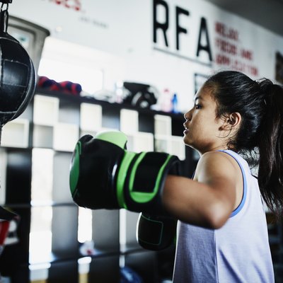 Young female boxer working on double ended bag in boxing gym