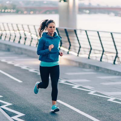 Urban fitness. Woman running by the river