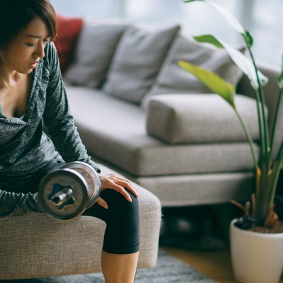 Japanese woman in fitness attire performing arm curls with dumbbell