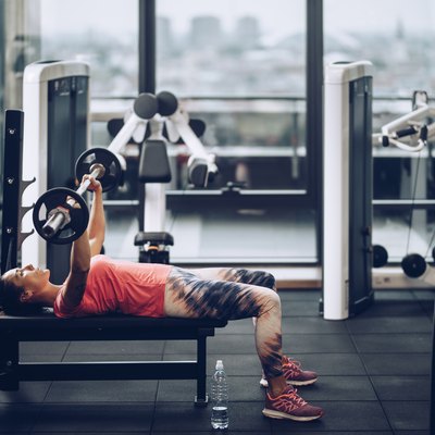 Young determined sportswoman exercising bench press in a gym.