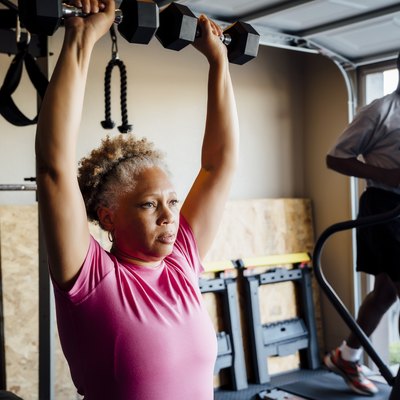 Couple lifting weights and doing cardio in their garage