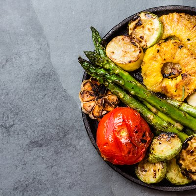 Grilled vegetables, pineapple slices and fresh cheese on iron plate