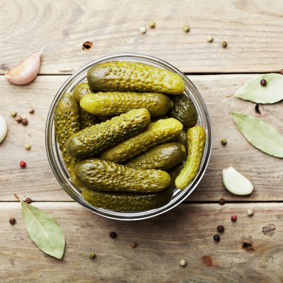 Pickled gherkins or cucumbers on wooden rustic table. Flat lay.
