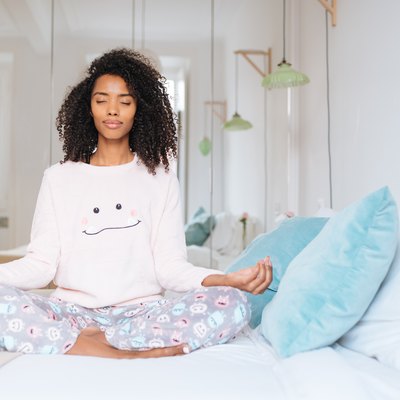 Happy beautiful young black woman relaxed at home doing morning meditation in bed 'n