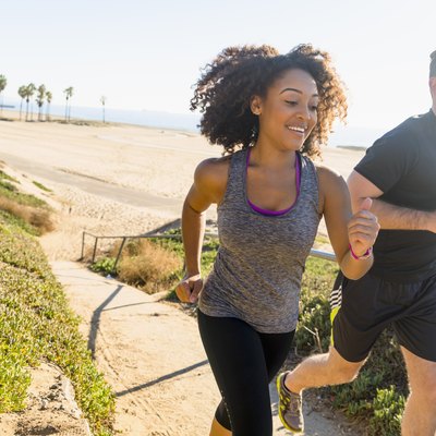 Couple runnExertion Headaches: A Pain, but Probably Not Dangerousing along pathway by beach