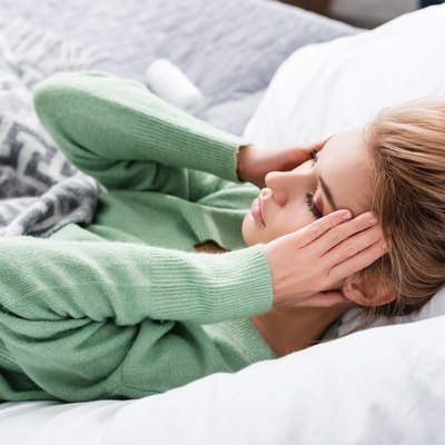 tired woman having headache and lying in bed in the morning