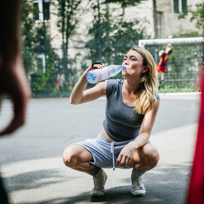Young Woman Taking Break From Basketball Game To Drink Water