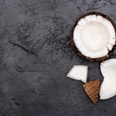 Top view of fresh healthy broken coconut on black background