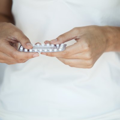 Woman holding birth control pills, mid section