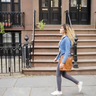 Mixed Race woman walking on city sidewalk
