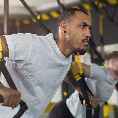 Men performing TRX exercises for upper body at the gym