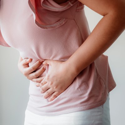 Midsection Of Woman With Stomachache Against Gray Background
