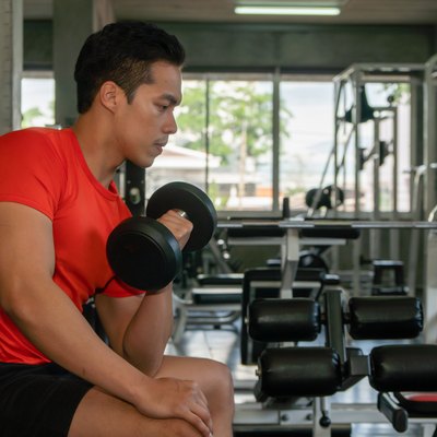 male having exercise lifting dumbbell in gym