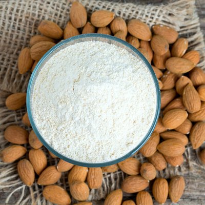 Almonds and almond flour on wooden surface