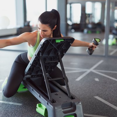 Woman training on step platform with dumbbells