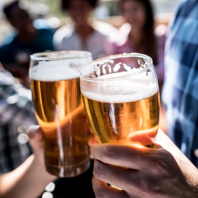 Close up of two people at a bar holding a beer and making a toast