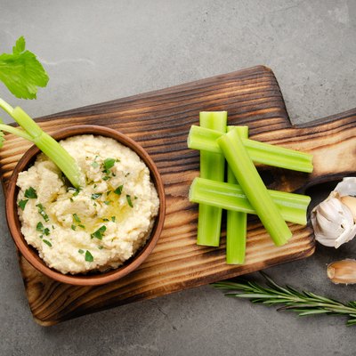 Flat lay view at vegetable Hummus dip dish topped with chickpeas and olive oil served with celery slices