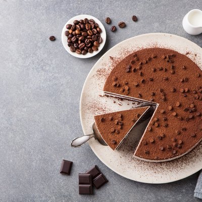 Tiramisu cake with chocolate decoration on a plate. Grey stone background. Top view. Copy space.