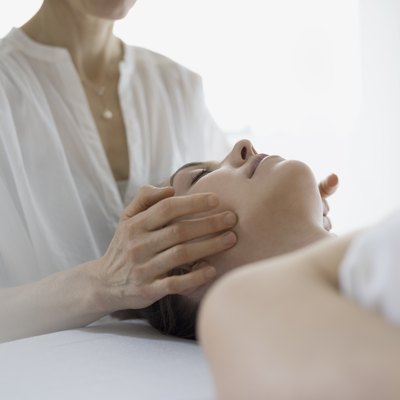 Serene woman receiving face massage on spa massage table