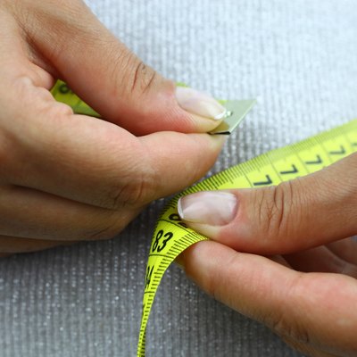 A close-up view of a woman measuring her waistline