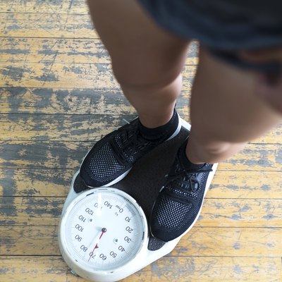 lower body of a man checking hypoglycemia's effect on weight gain or loss on a scale