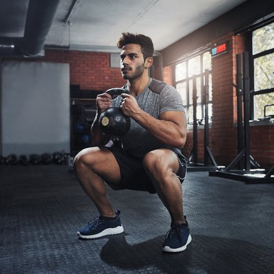 Man doing squats with a kettlebell in the gym