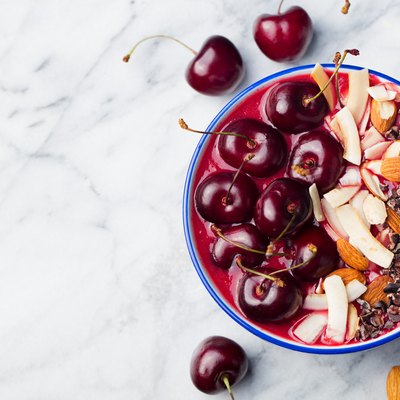 Smoothie bowl with fresh black cherries, coconut flakes, almond.
