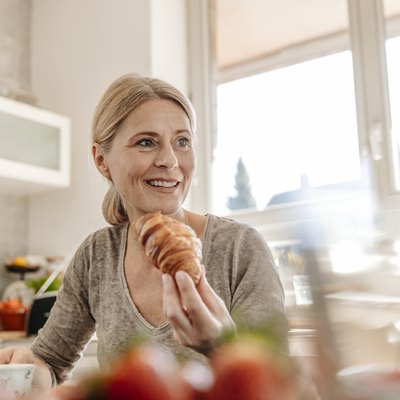 Woman at home eating a croissant