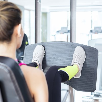Female fitness instructor working out Leg press in health club
