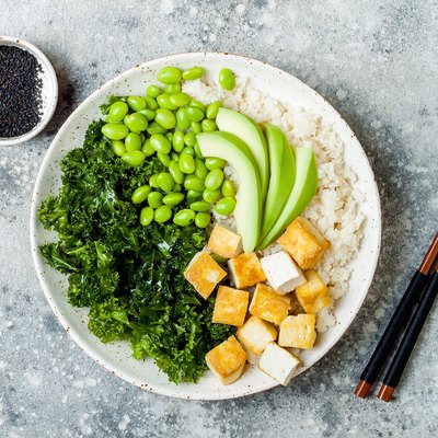 Cauliflower rice Buddha bowl with massaged kale, tofu, avocado and edamame beans. Vegan poke bowl