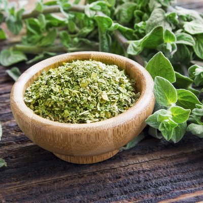 Fresh and dried oregano herb on wooden background