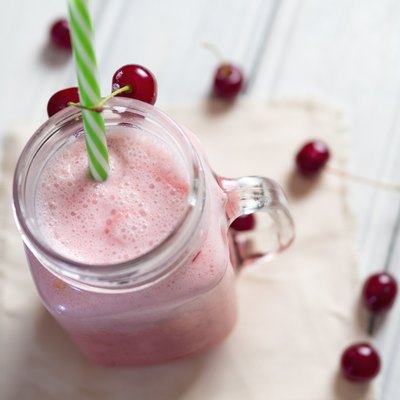 Milkshake or cherry smoothie on white wooden table. Wholesome breakfast