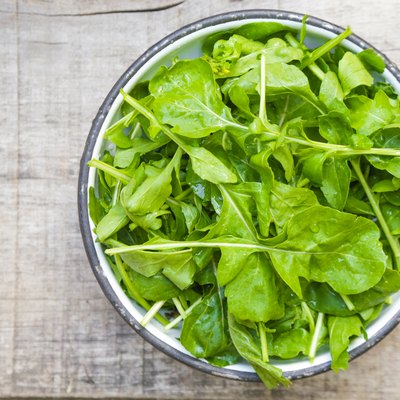 Fresh rucola salad in a bowl on the wooden background