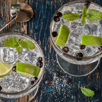 Directly Above Shot Of Juniper Berries And Lemon Slices In Gin and Tonic Glasses On Table