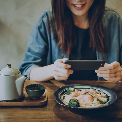 Smiling woman capturing her meal on table with smartphone in cafe