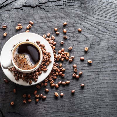 Cup of coffee surrounded by coffee beans.