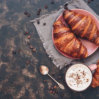 Croissants with coffee on a dark surface, top view, copy space.