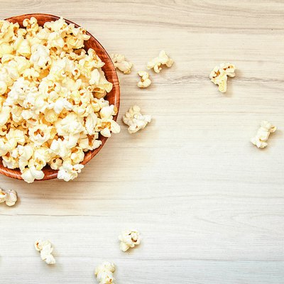 Salt popcorn in the wooden bowl on the wooden table.