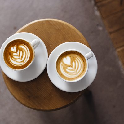 Directly above view of two coffee cups with latte art on the round table