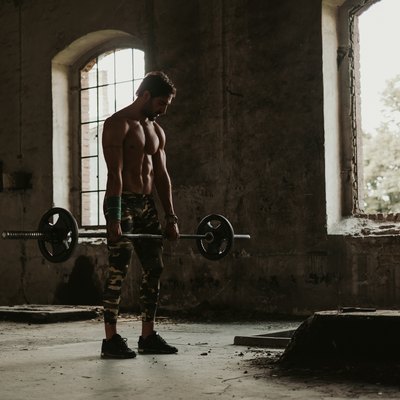 Athletic man holding weights in deadlift in an old building