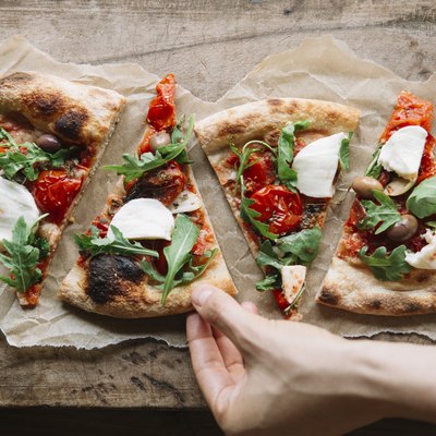 Woman taking healthy pizza recipes from chopping board, overhead view