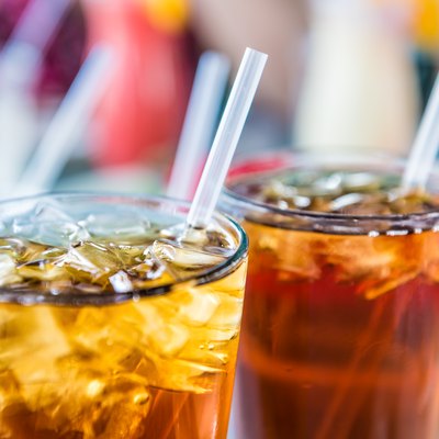Macro closeup of iced tea or soda with ice cubes and straw in glass