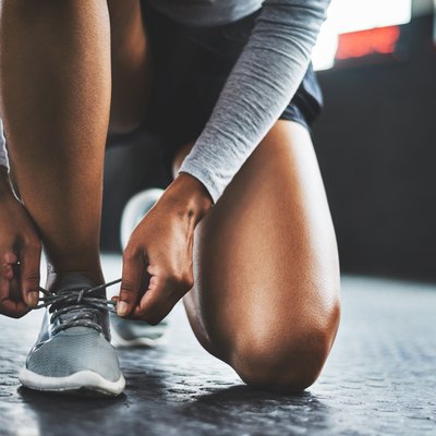 Women kneeling tying running sneakers