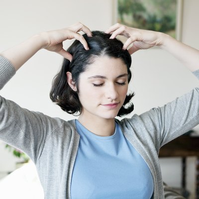 A woman with short brown hair performing a scalp exercise at home
