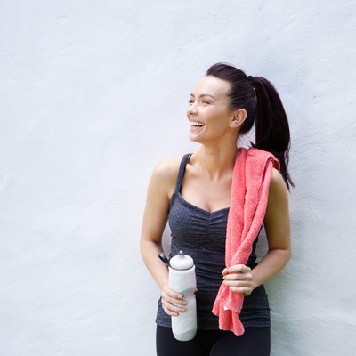 Smiling sporty woman with water bottle and towel