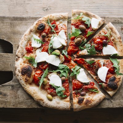 Sliced pizza on chopping board, overhead view
