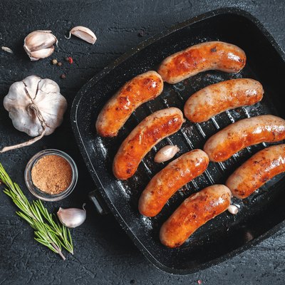 Top view on fried sausages in a black frying pan on a black stone table